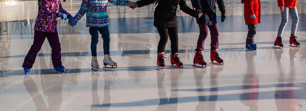 Kids hold hands while skating on an outdoor rink